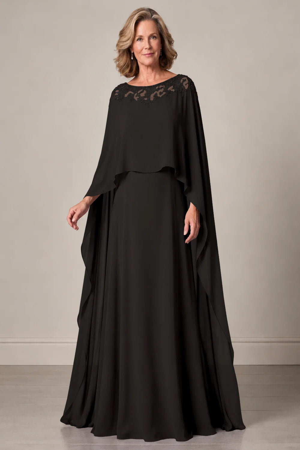 Front view of a black dress with a decorated neckline and long cape panels.