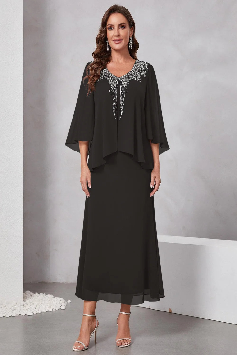 Front view of a black dress with a decorated neckline and short upper overlay.
