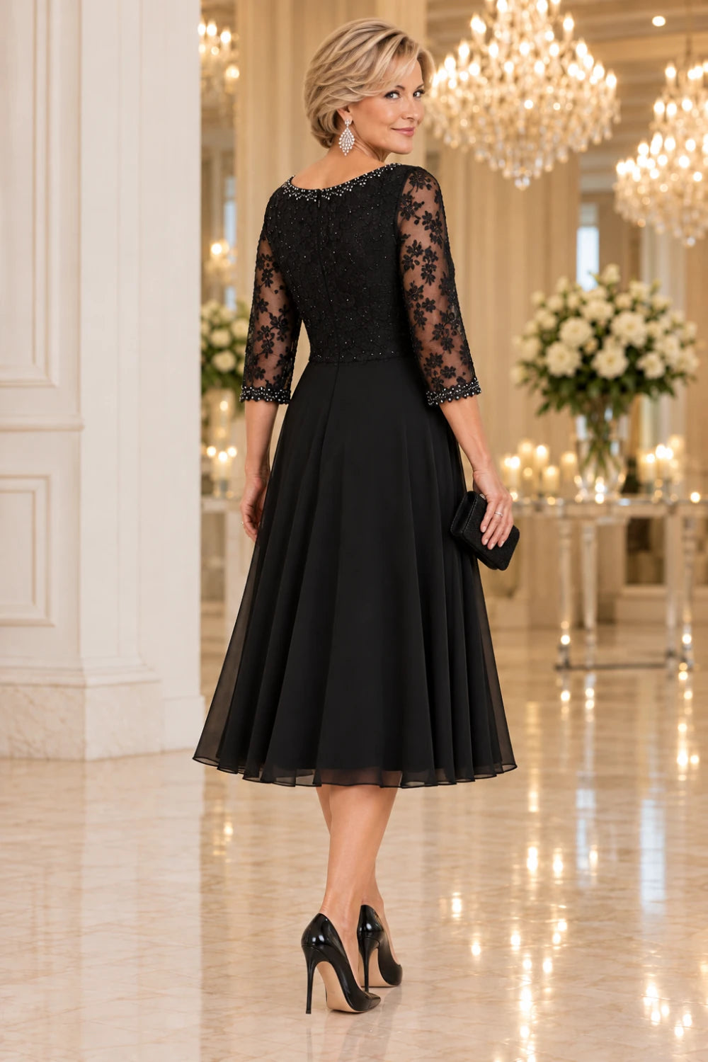 Rear three-quarter view of the black dress with floral lace across the back and a plain below-knee skirt.