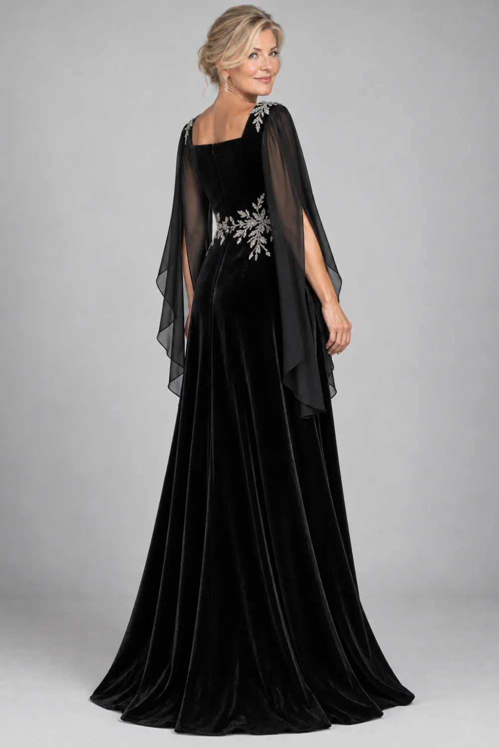 Back view of a black a-line gown with long sheer split cape sleeves.