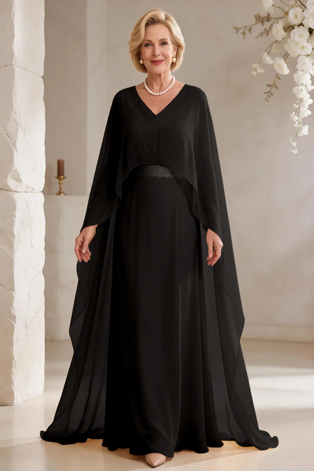 Front view of a black dress with long cape panels and a flared skirt.