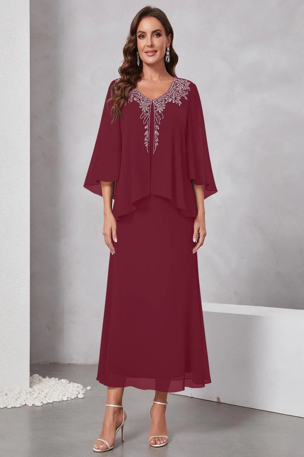 Front view of a burgundy dress with a decorated neckline and short upper overlay.
