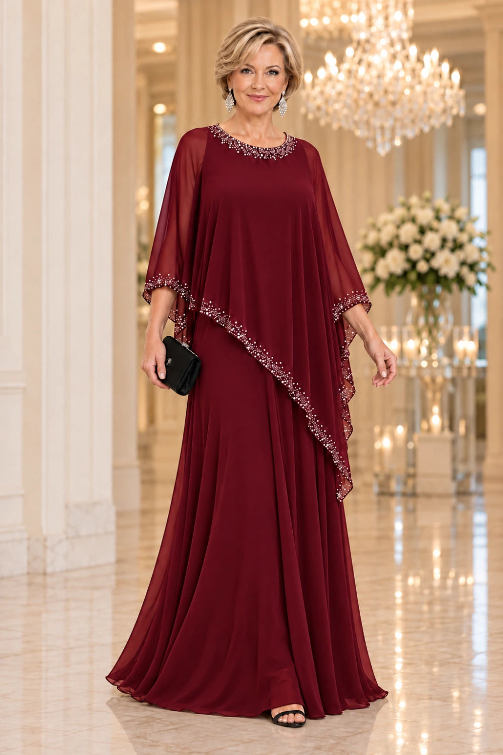 Burgundy gown with a long flared skirt and diagonal sheer cape, front view.