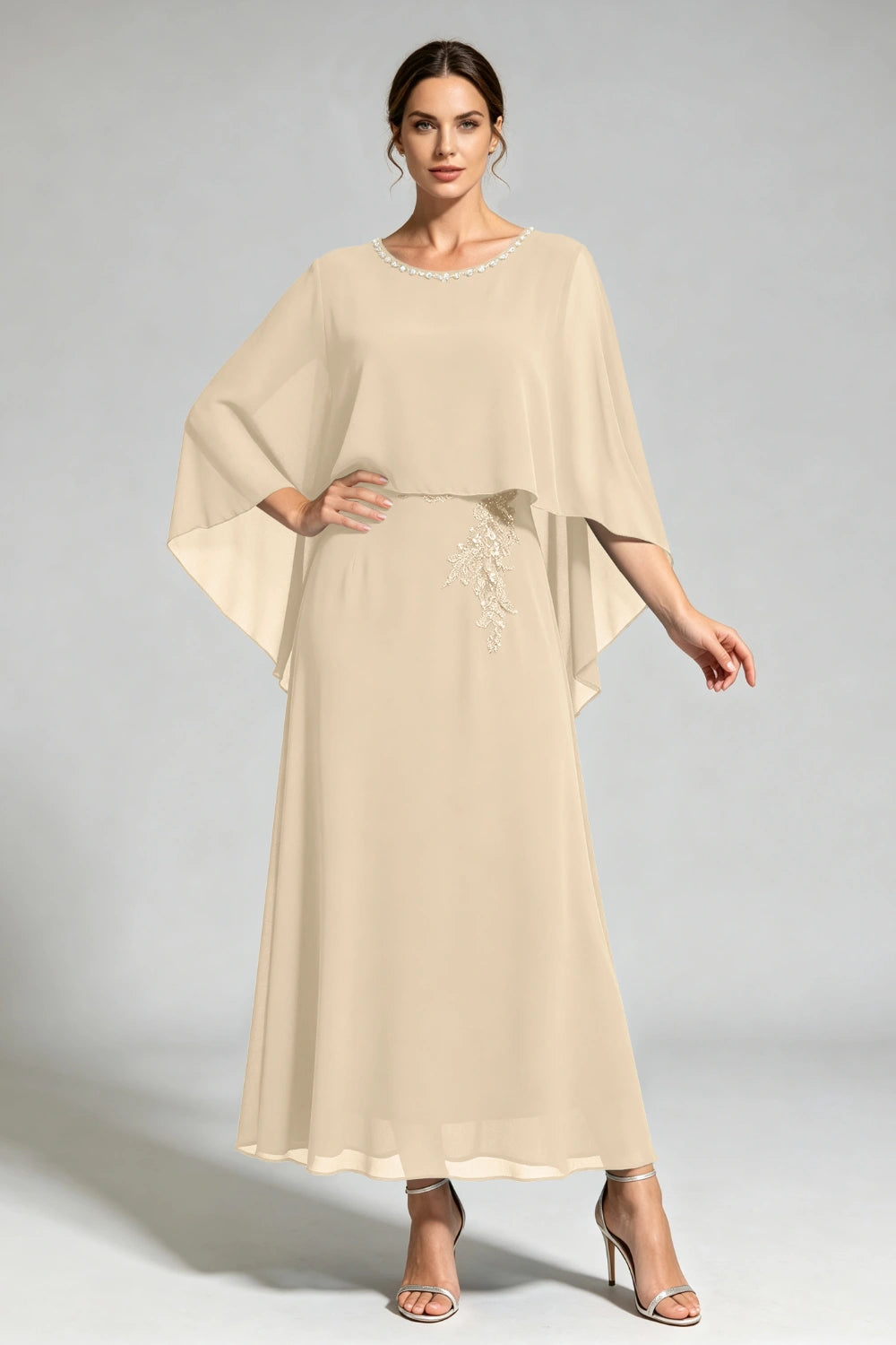 Front view of the champagne cape dress with a beaded round neckline and tonal floral applique.