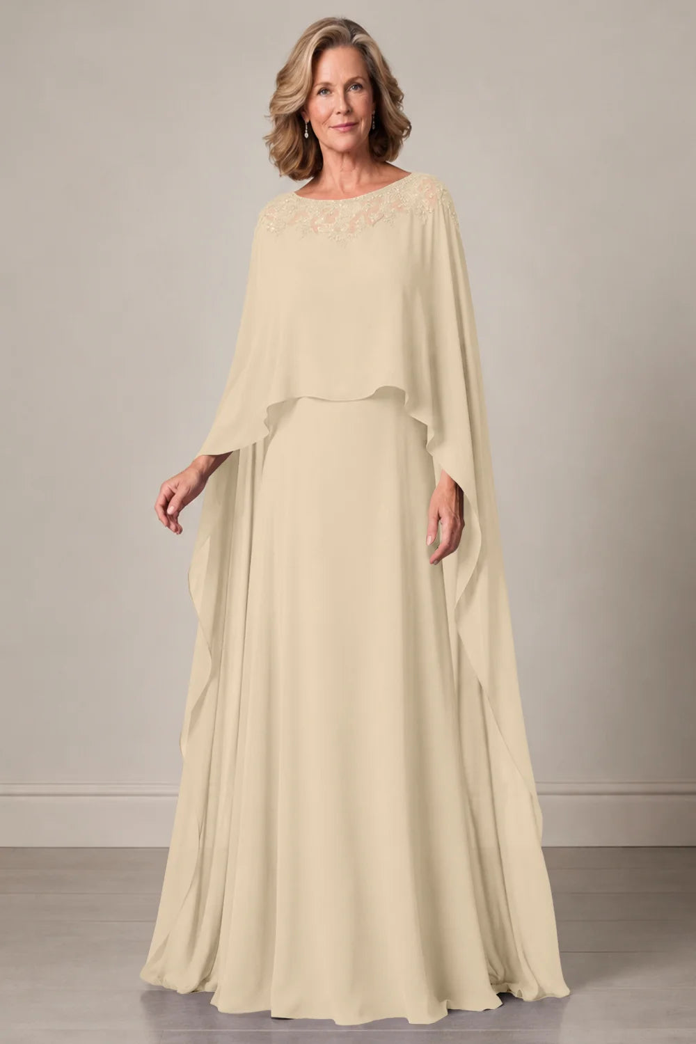 Front view of a champagne dress with a decorated neckline and long cape panels.