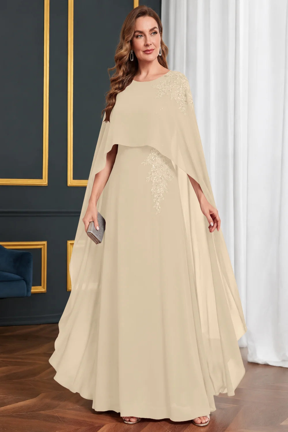Front view of a champagne dress with long cape panels and shoulder decoration.