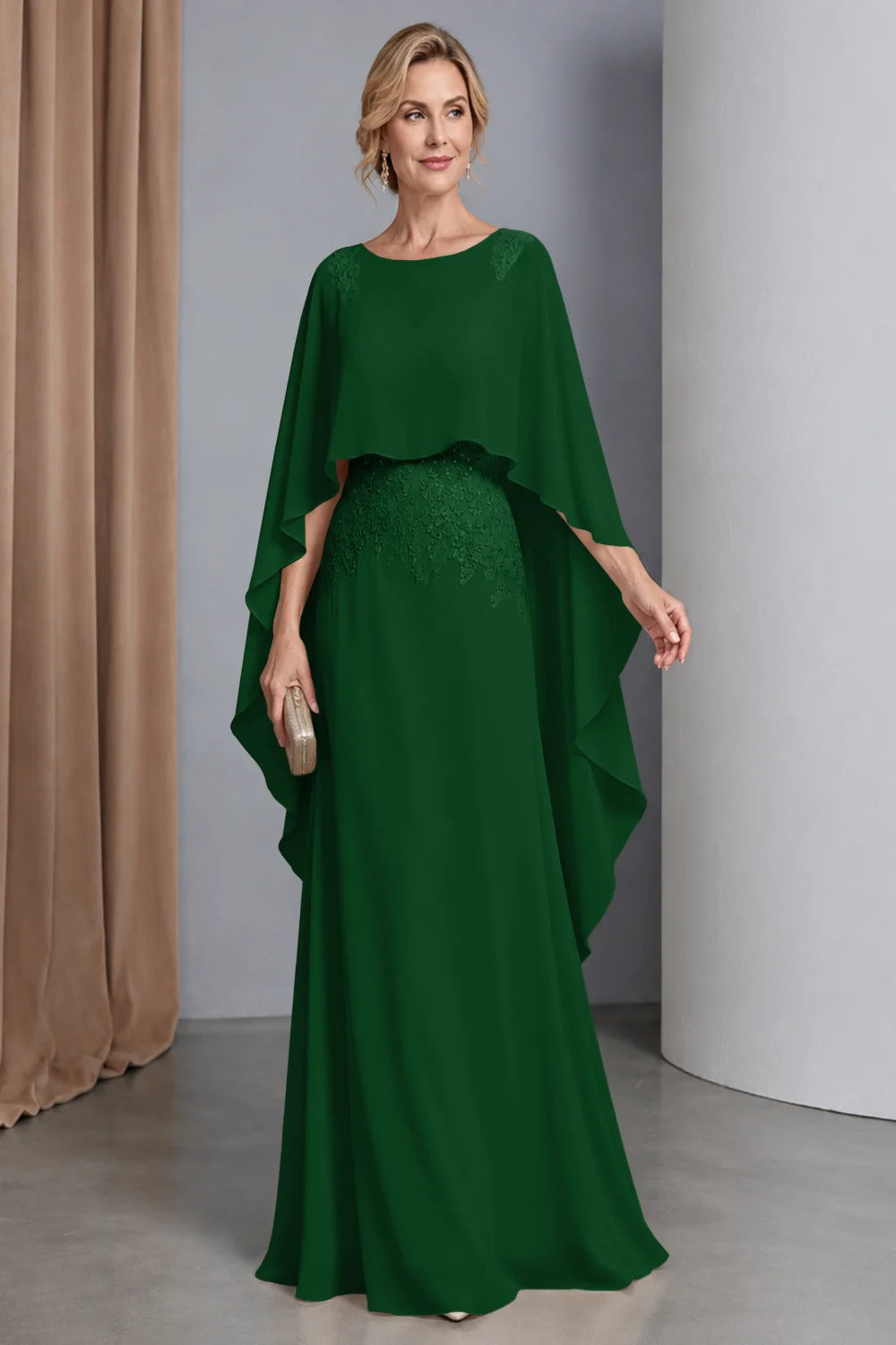 Front view of a emerald green dress with a curved cape front and embellished waist.