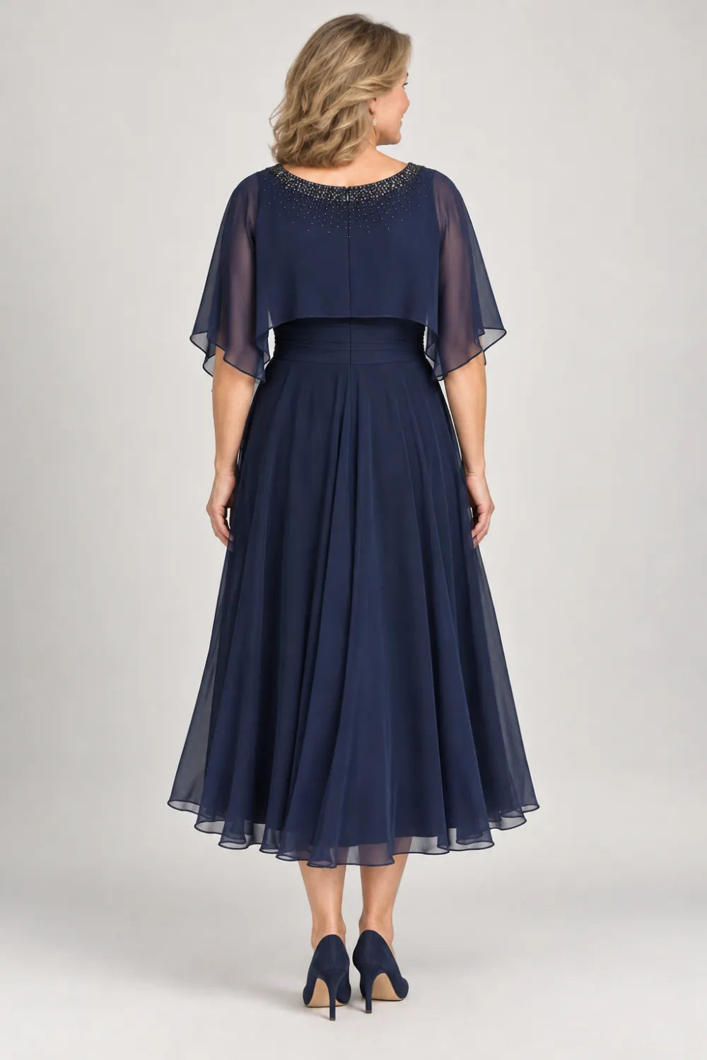 Back view of a navy blue tea-length a-line dress with short sheer shoulder capelet.