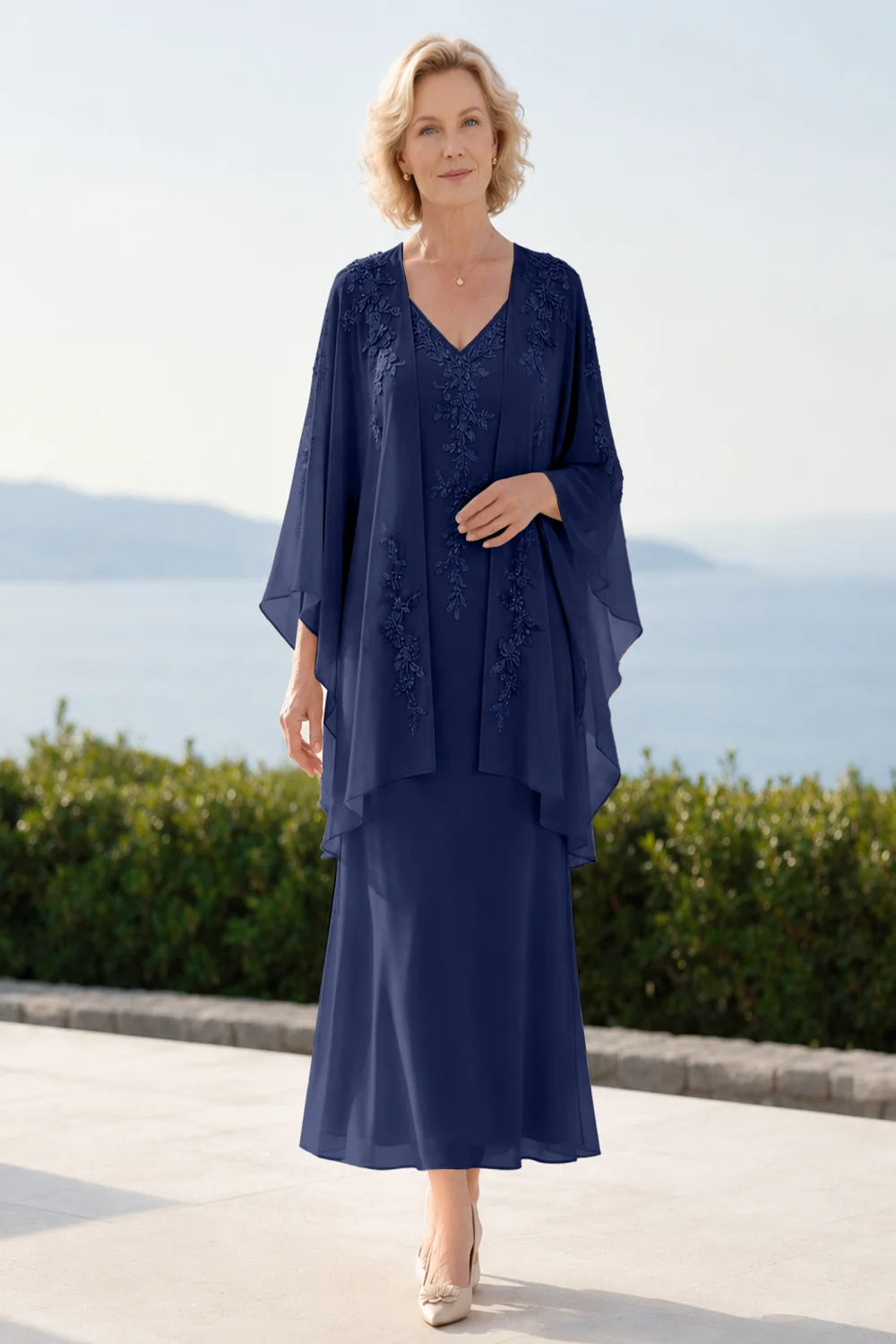 Front view of a navy blue dress with a decorated neckline and long upper overlay.