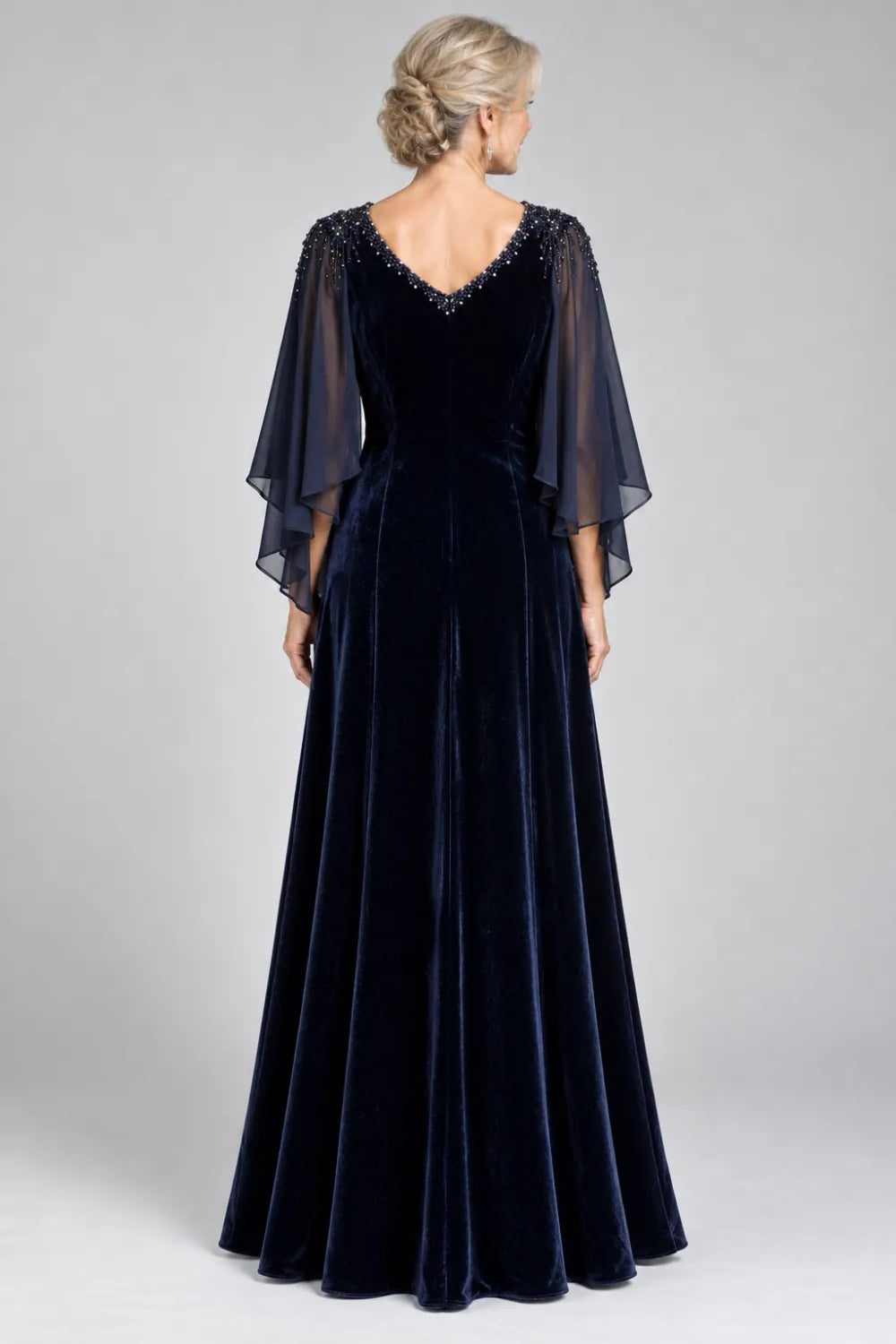 Back view of a navy blue floor-length gown with layered sheer cape.