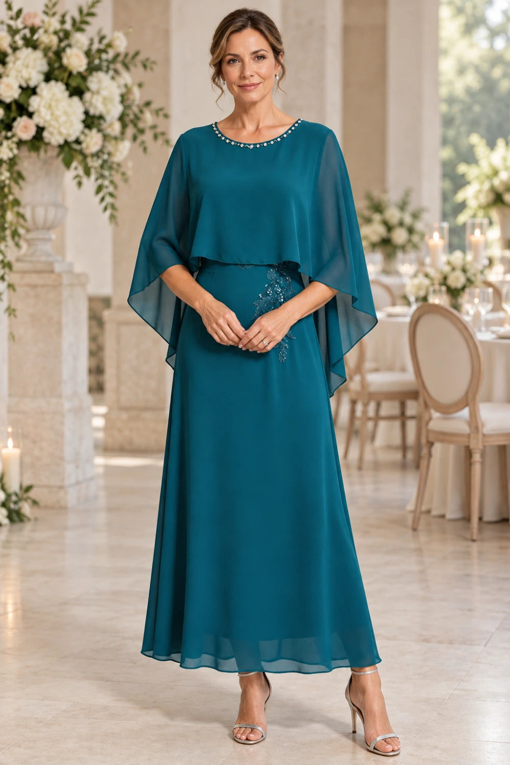 Front view of the peacock cape dress with a beaded round neckline and tonal floral applique.
