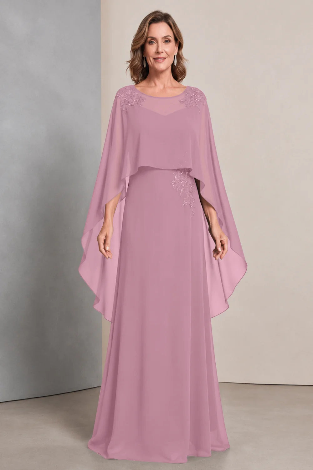 Front view of a pink dress with a sheer neckline and long cape sides.