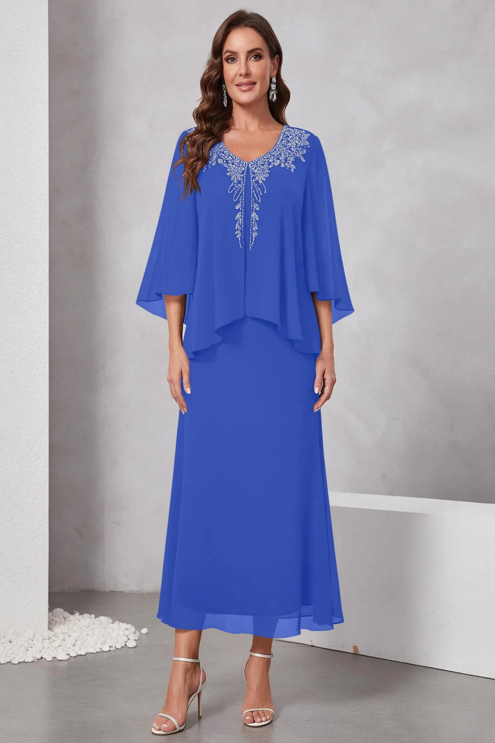 Front view of a royal blue dress with a decorated neckline and short upper overlay.