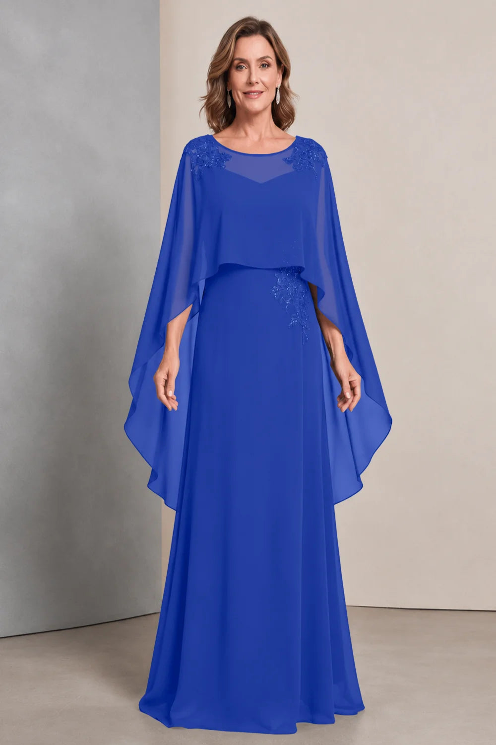 Front view of a royal blue dress with a sheer neckline and long cape sides.