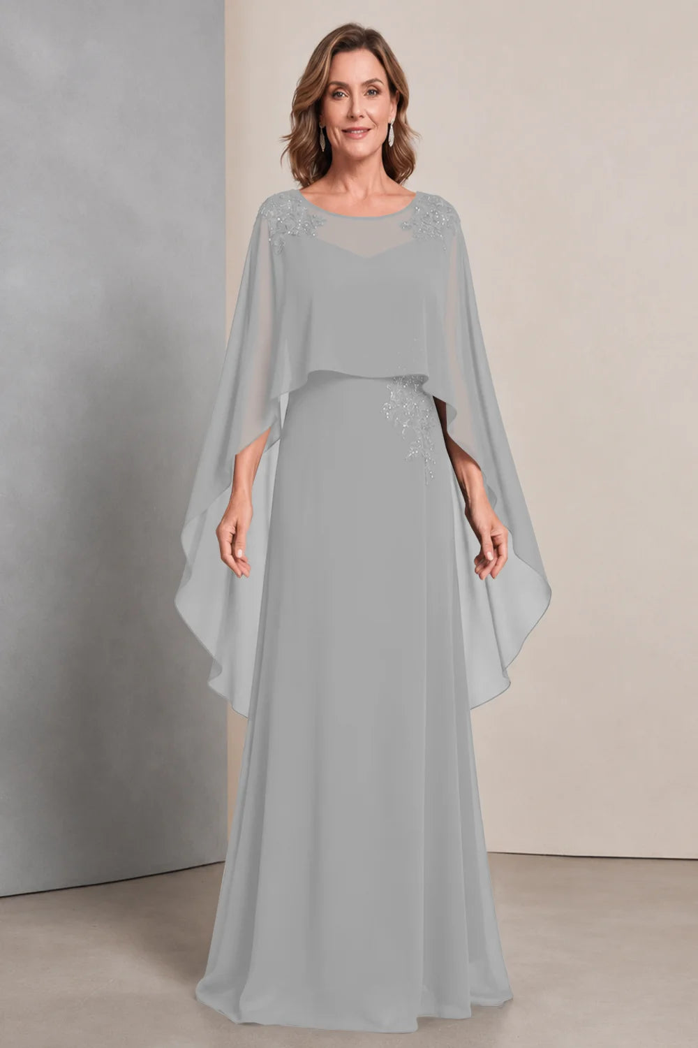 Front view of a silver gray dress with a sheer neckline and long cape sides.