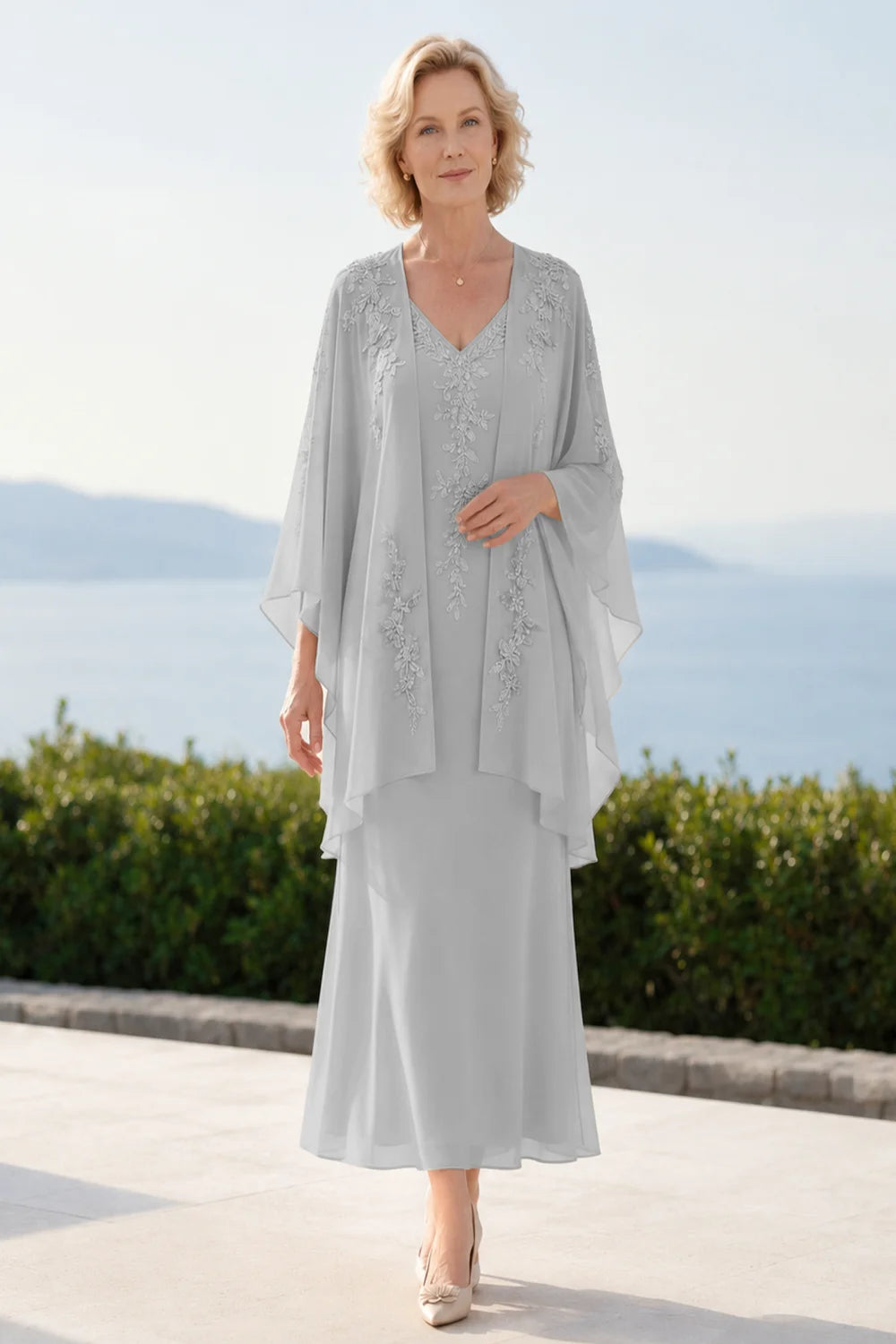 Front view of a silver gray dress with a decorated neckline and long upper overlay.