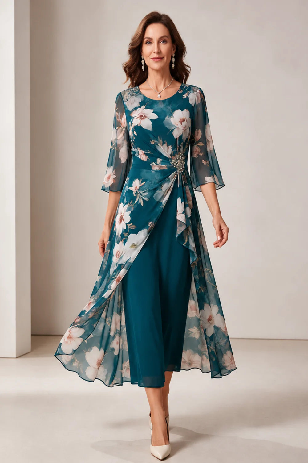 Front view of a teal dress with a floral overlay and flared sleeves.