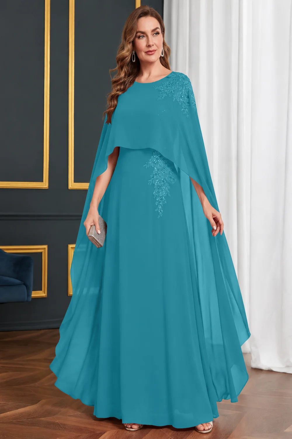 Front view of a teal dress with long cape panels and shoulder decoration.