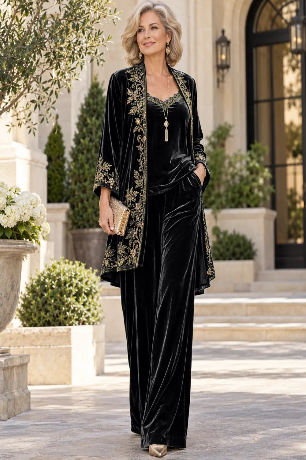 Front view of a black pant suit with a floral-bordered long jacket and matching trousers.