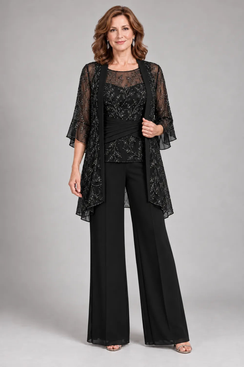 Black pant suit with floral lace top and diagonal gathered waist, front view.
