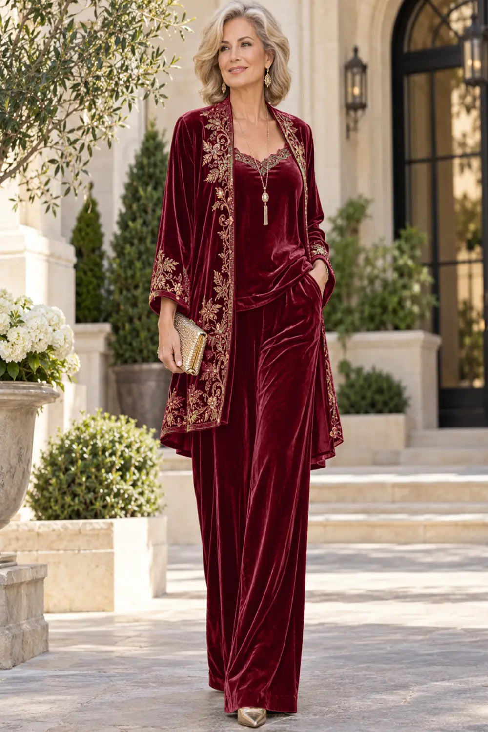 Front view of a burgundy pant suit with a floral-bordered long jacket and matching trousers.