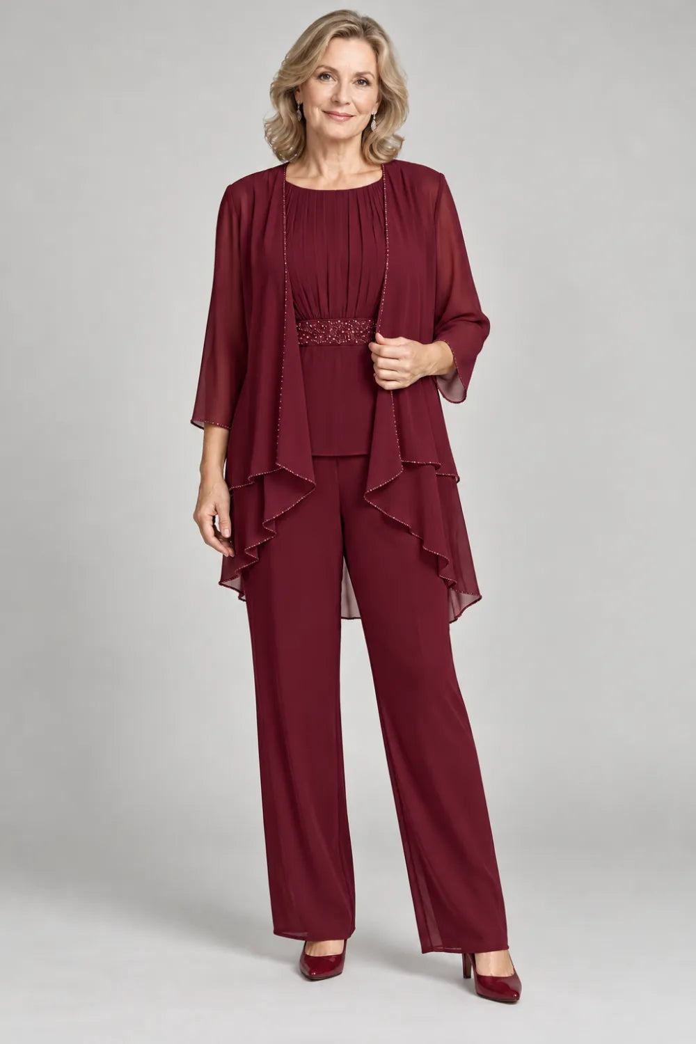 Burgundy pant suit with gathered top and decorated horizontal waist band, front view.