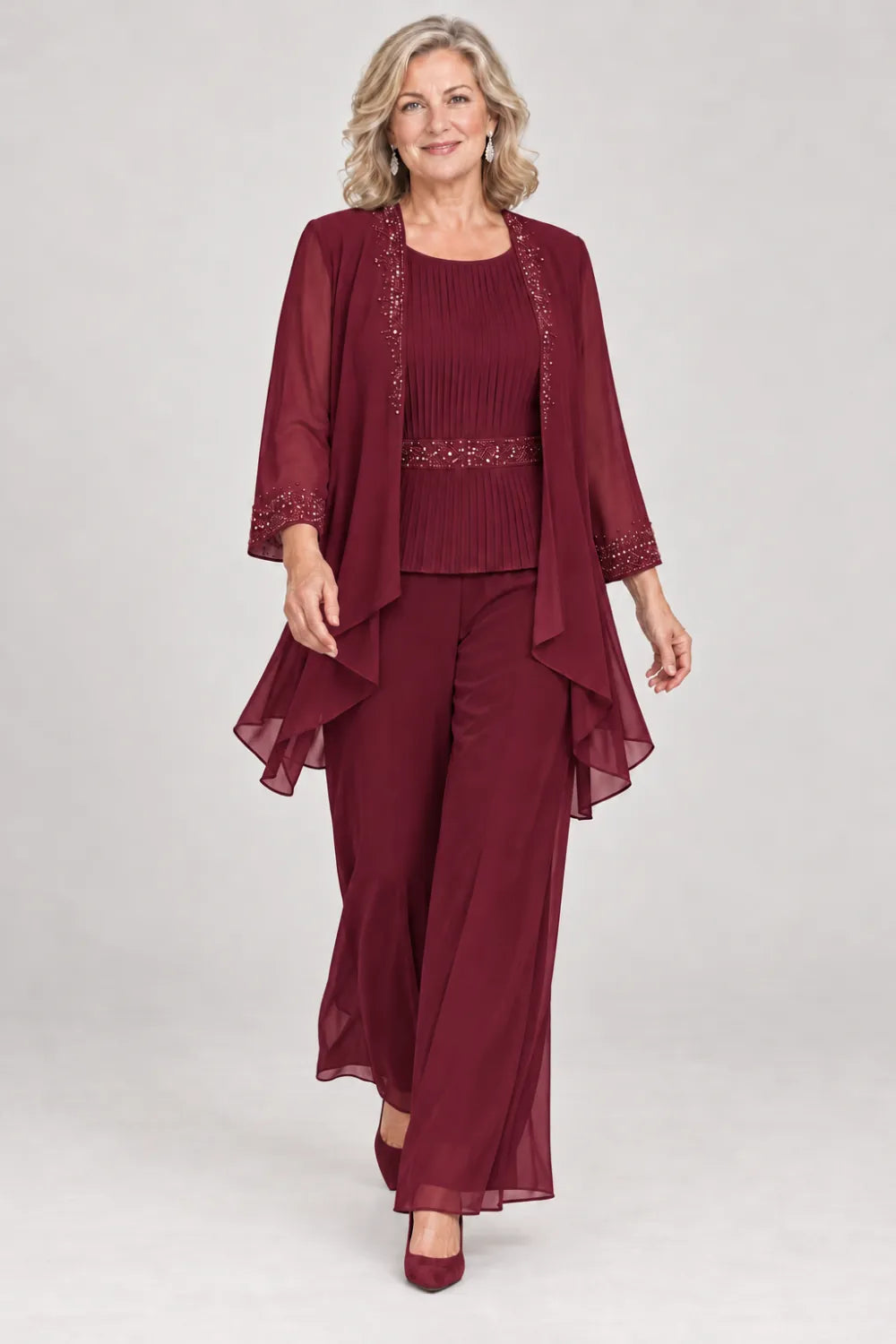 Burgundy pant suit with pleated top and beaded waist, jacket edges and cuffs, front view.