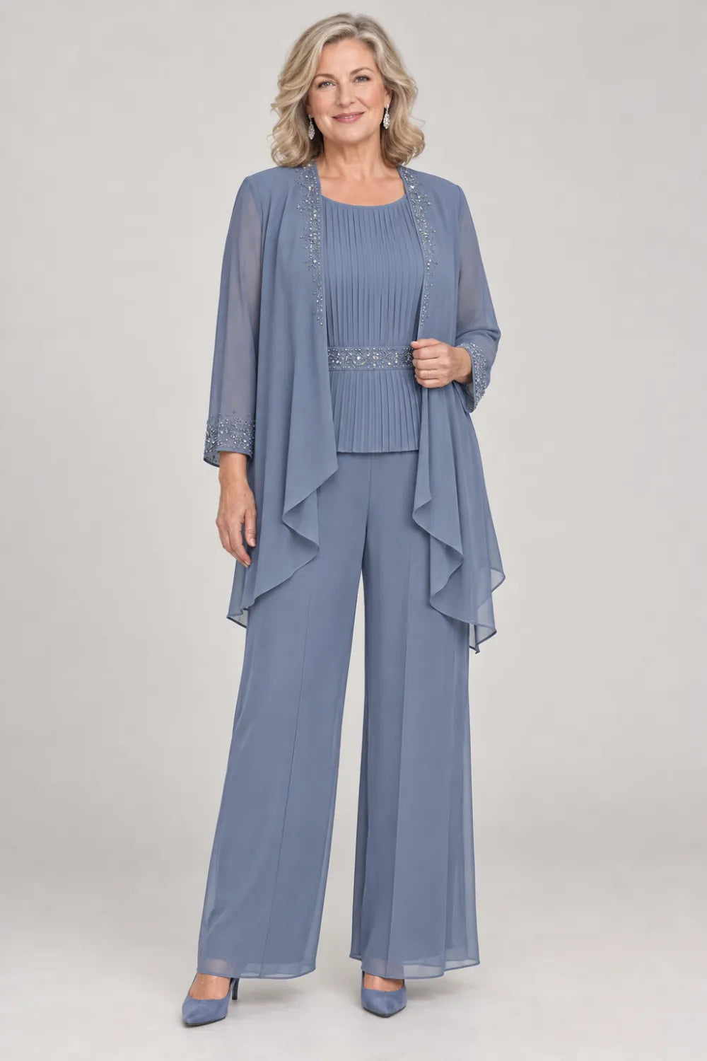 Dusty Blue pant suit with pleated top and beaded waist, jacket edges and cuffs, front view.