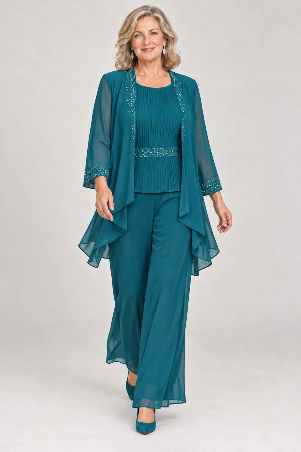 Teal pant suit with pleated top and beaded waist, jacket edges and cuffs, front view.
