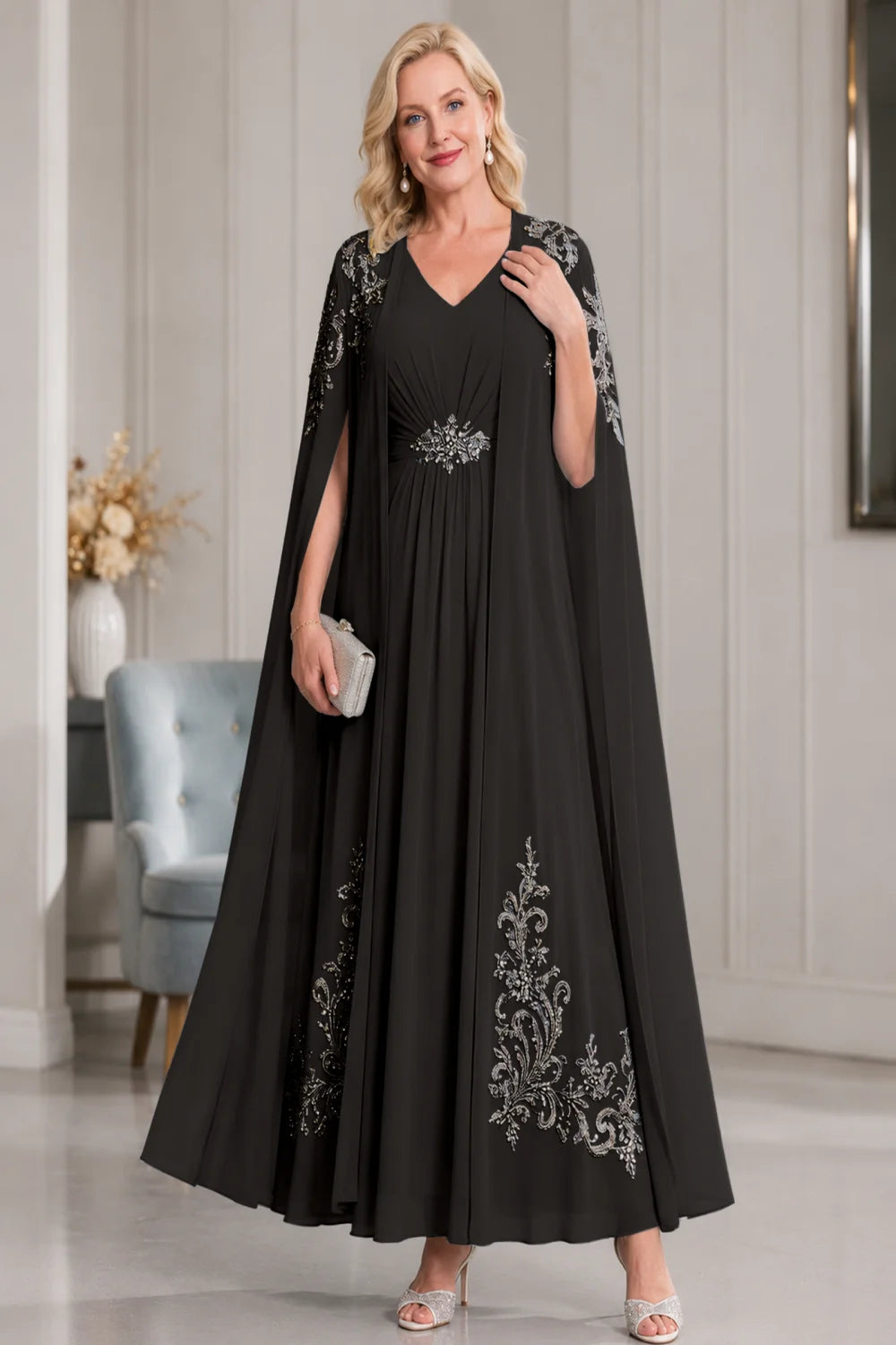 Front view of a black dress with open cape panels and pale skirt motifs.