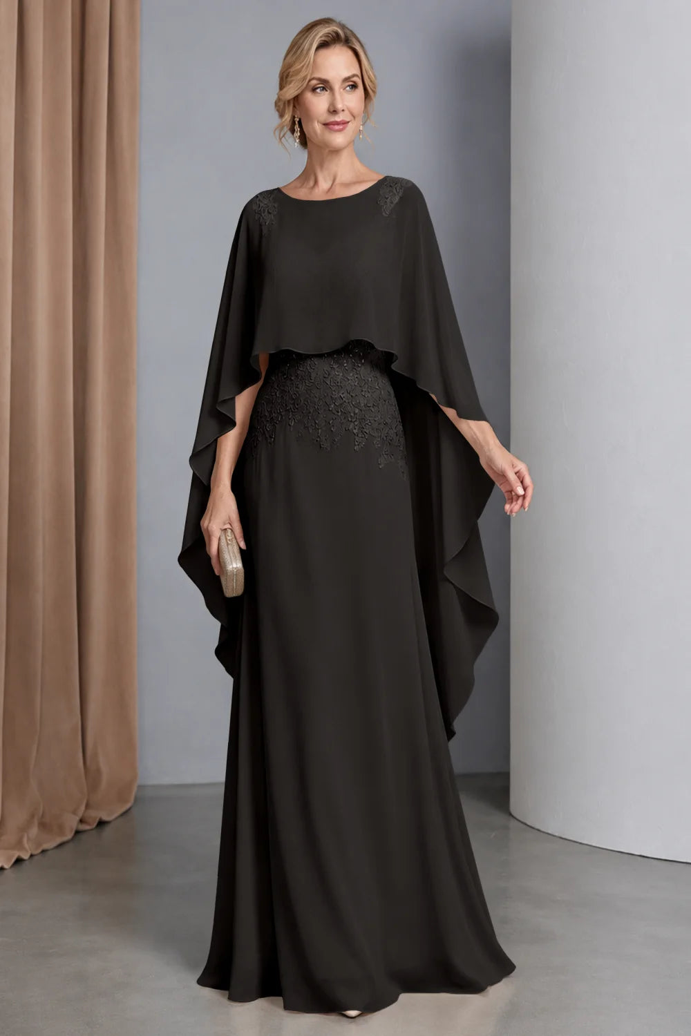 Front view of a black dress with a curved cape front and embellished waist.