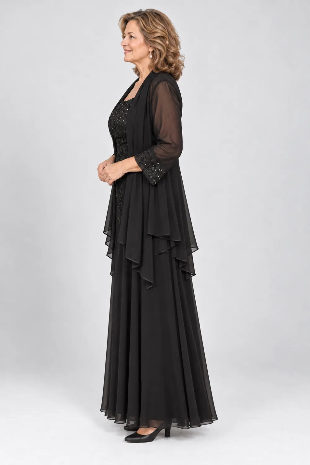 Black dress with floral bodice and matching decorated cuffs, side view.