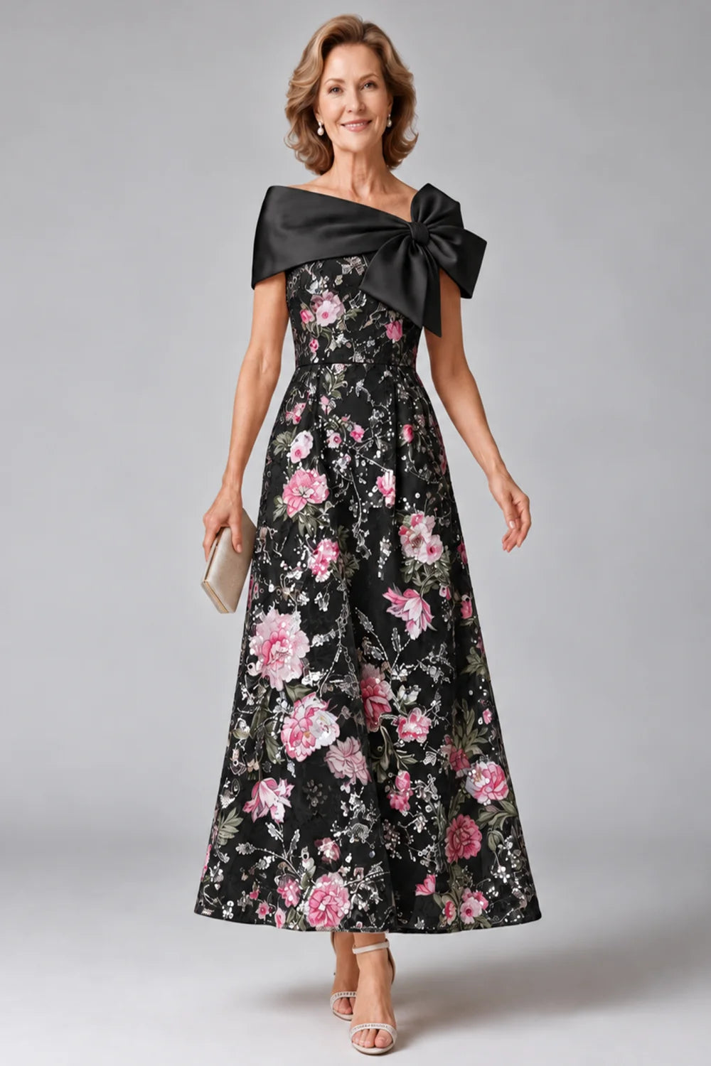 Front view of a black dress with a broad neckline bow and floral skirt.