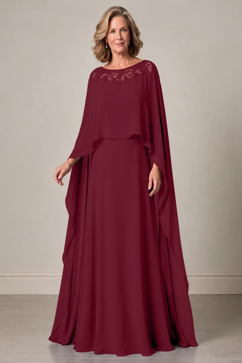 Front view of a burgundy dress with a decorated neckline and long cape panels.