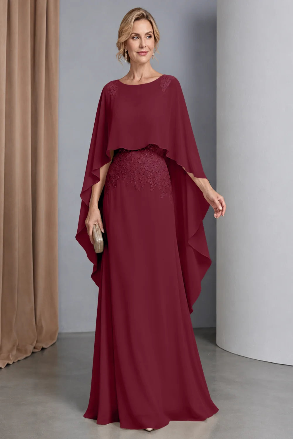 Front view of a burgundy dress with a curved cape front and embellished waist.