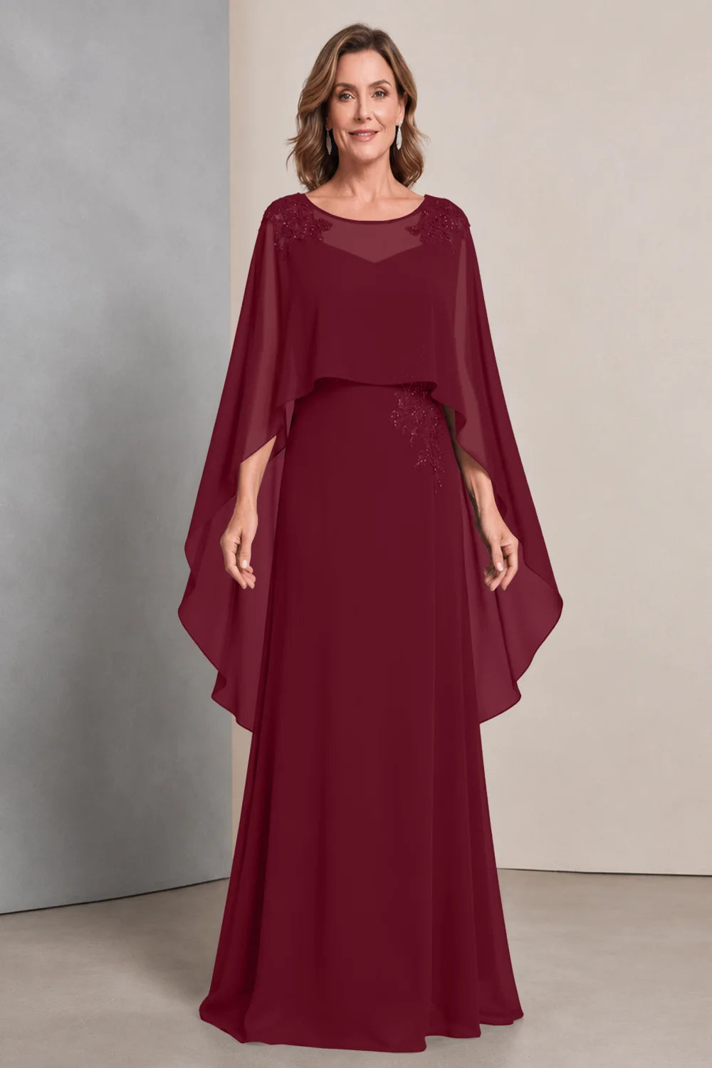 Front view of a burgundy dress with a sheer neckline and long cape sides.