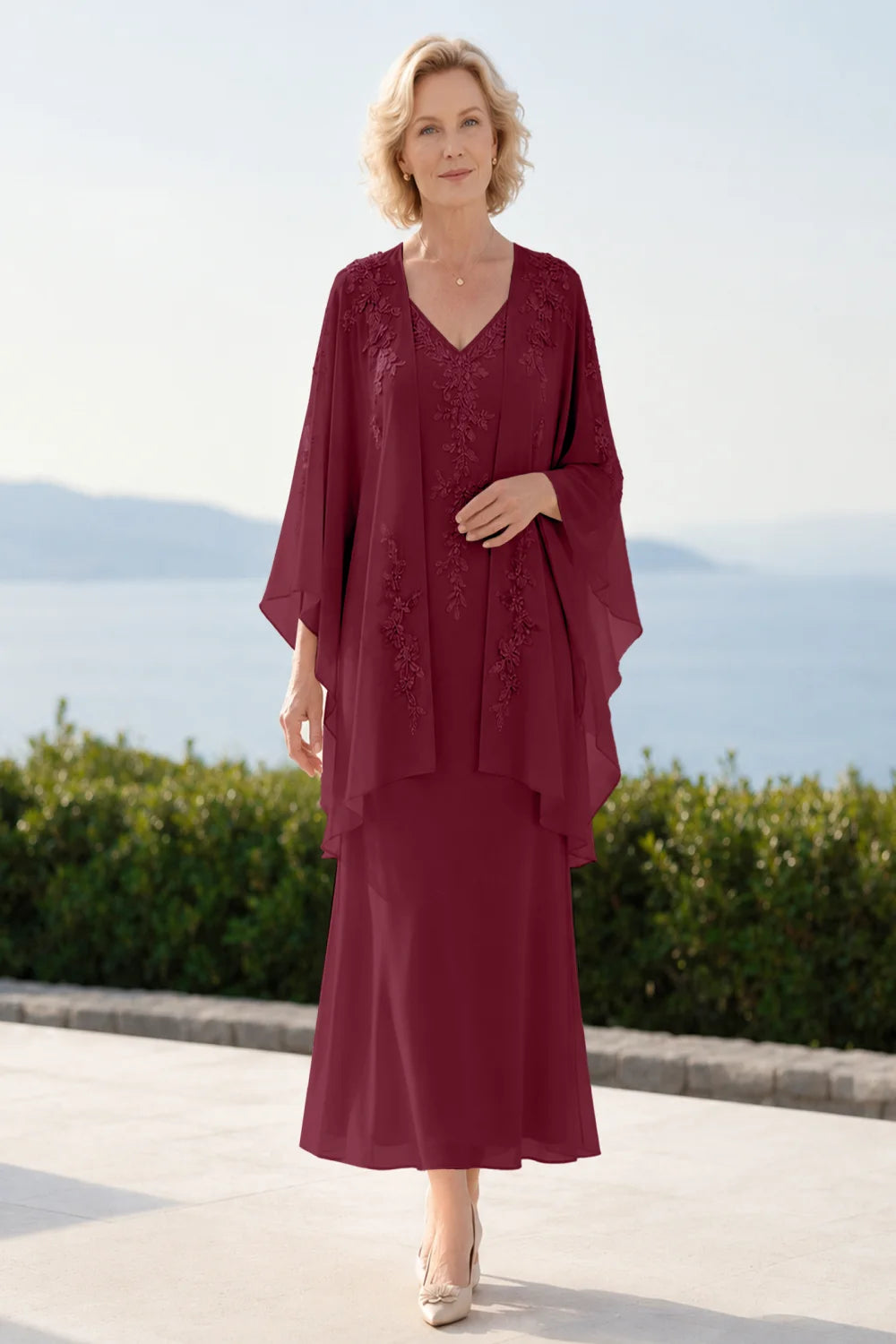 Front view of a burgundy dress with a decorated neckline and long upper overlay.