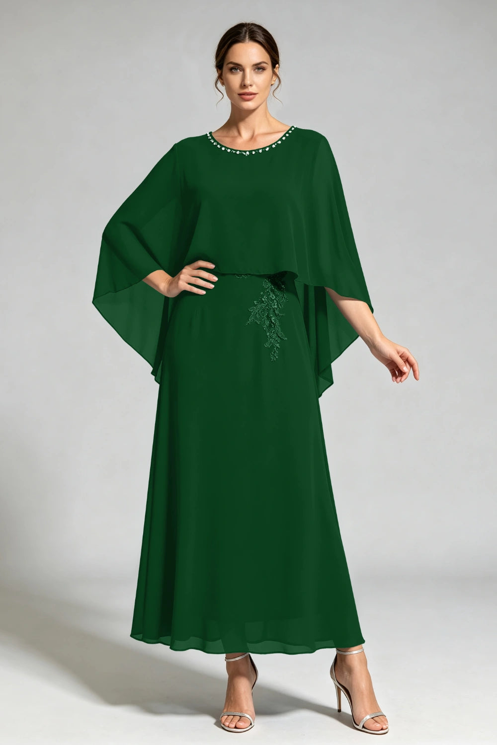 Front view of the dark green cape dress with a beaded round neckline and tonal floral applique.