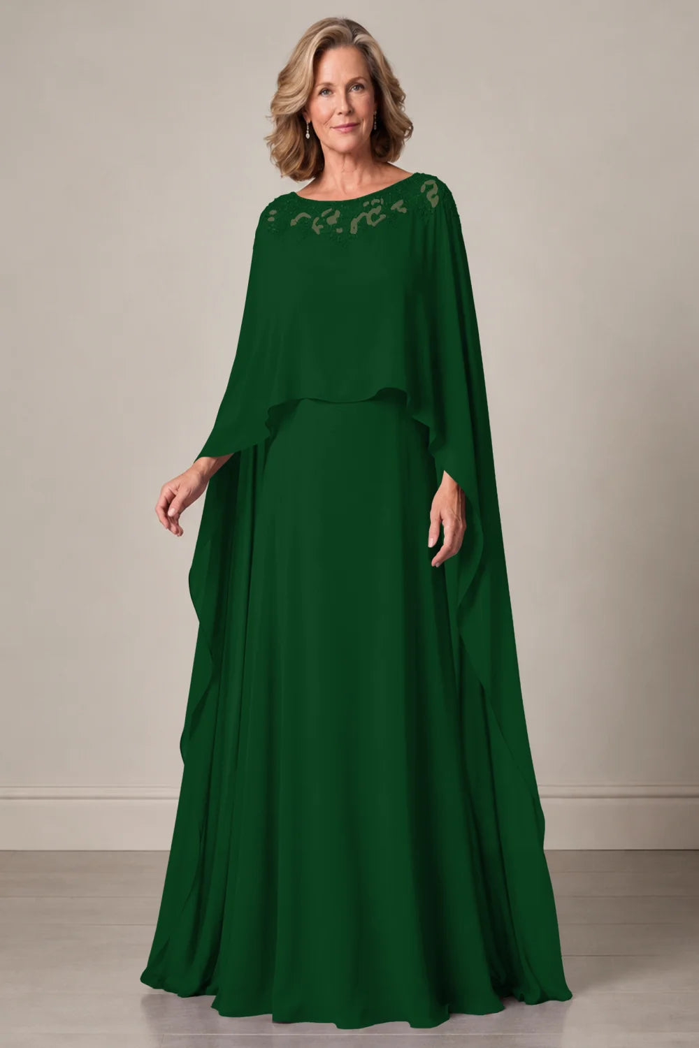 Front view of a emerald green dress with a decorated neckline and long cape panels.