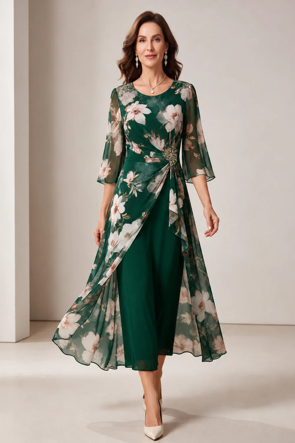 Front view of a emerald green dress with a floral overlay and flared sleeves.