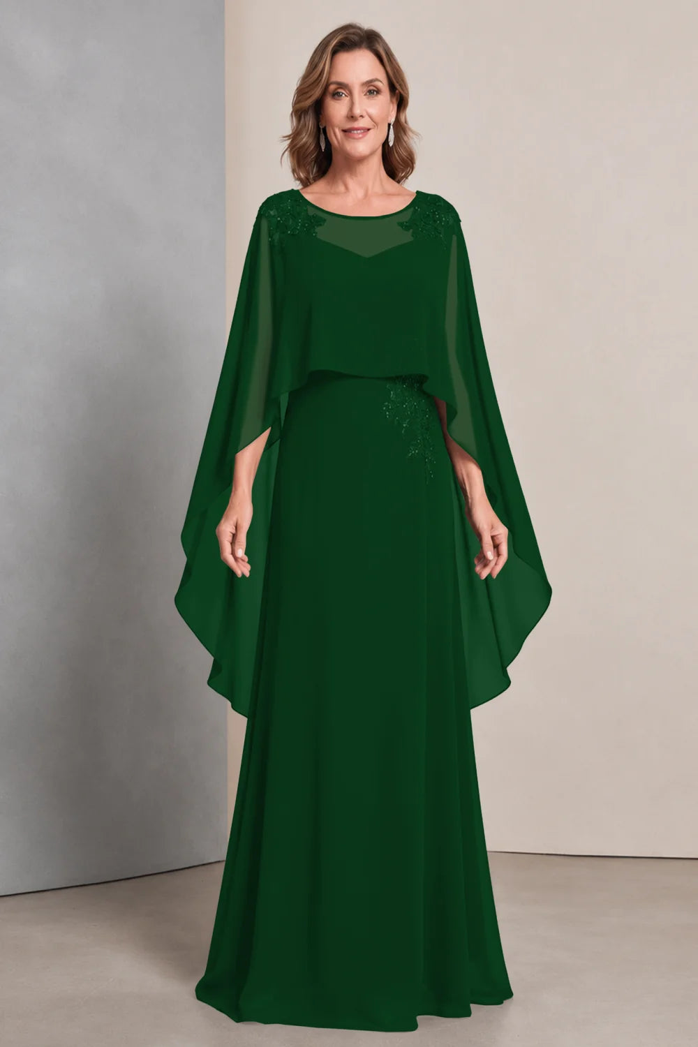 Front view of a emerald green dress with a sheer neckline and long cape sides.