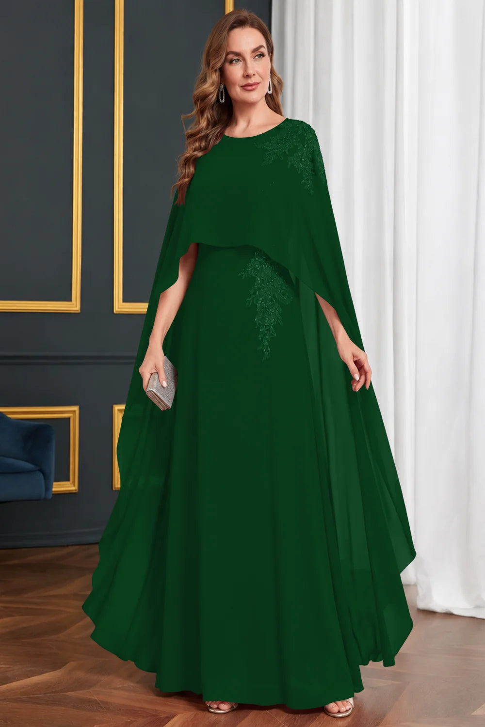 Front view of a emerald green dress with long cape panels and shoulder decoration.