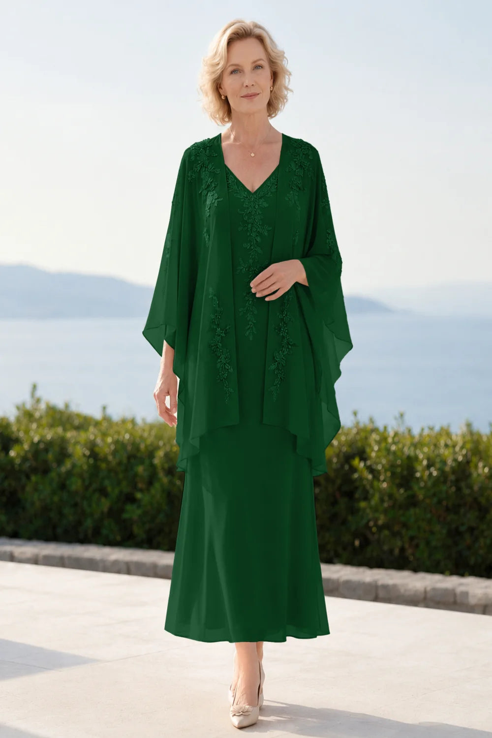 Front view of a emerald green dress with a decorated neckline and long upper overlay.