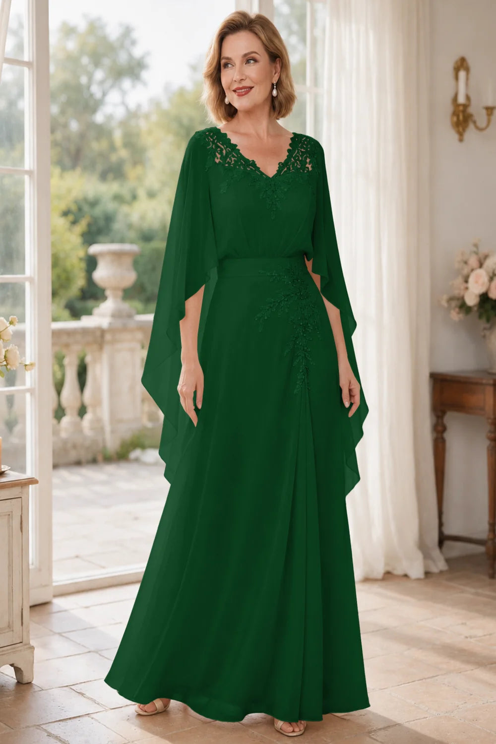 Front view of a emerald green dress with a lace V neckline and open cape panels.