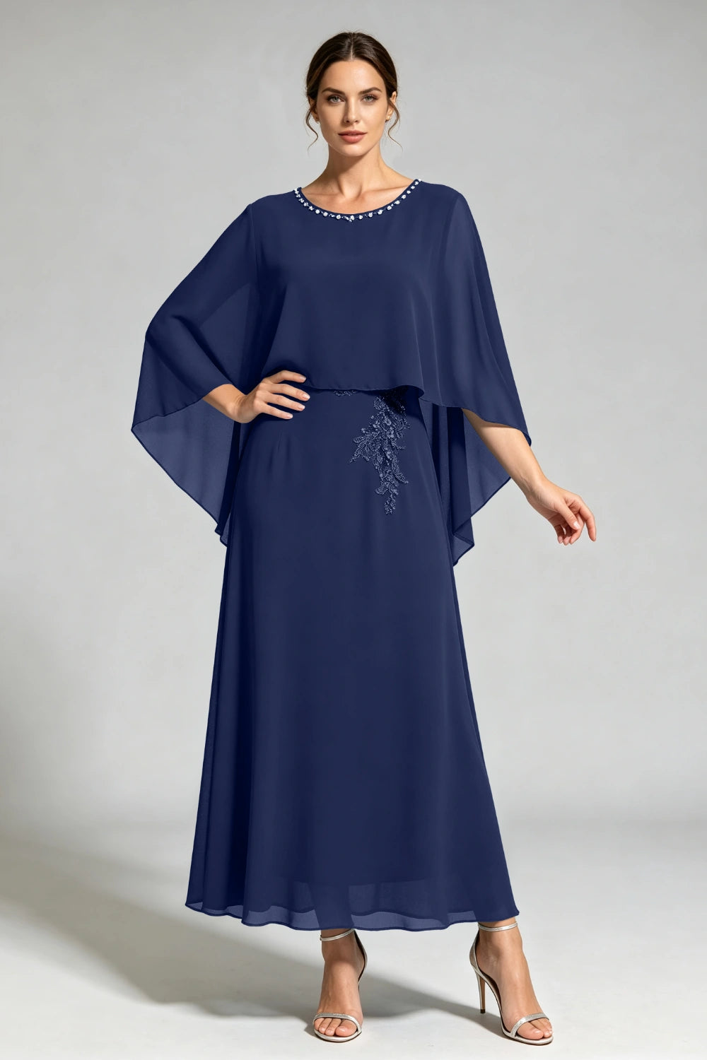 Front view of the navy cape dress with a beaded round neckline and tonal floral applique.