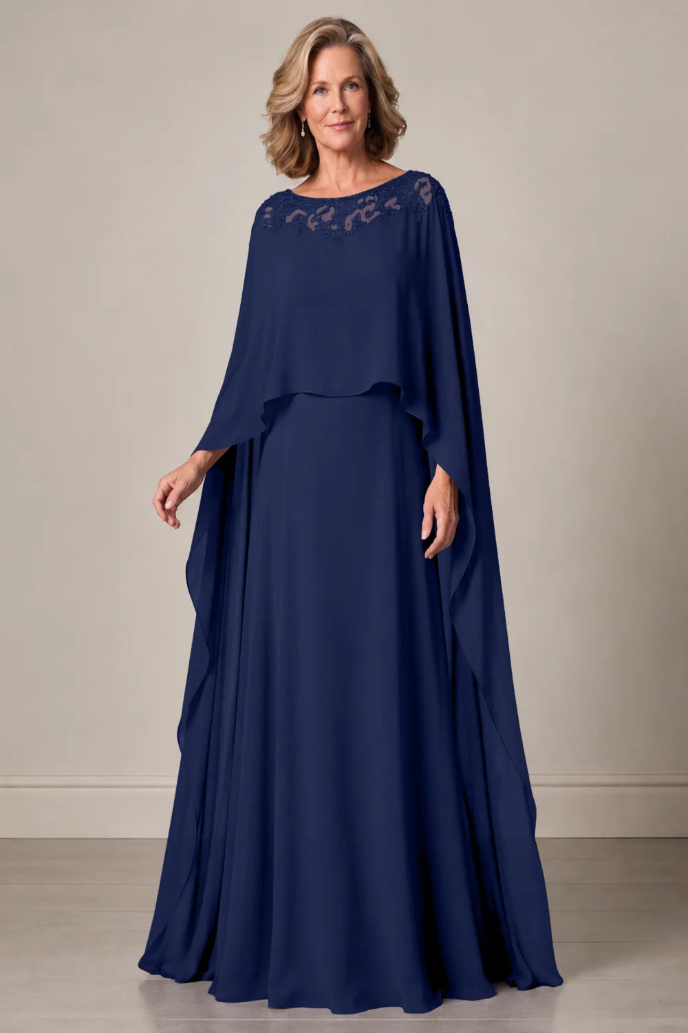 Front view of a navy blue dress with a decorated neckline and long cape panels.