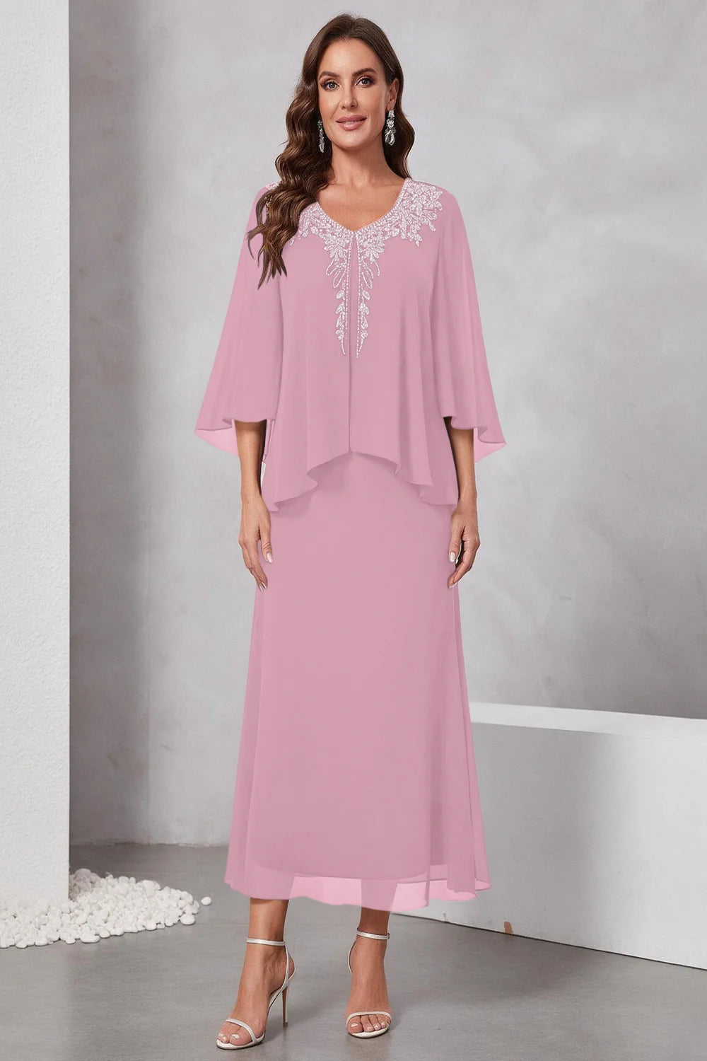 Front view of a pink dress with a decorated neckline and short upper overlay.