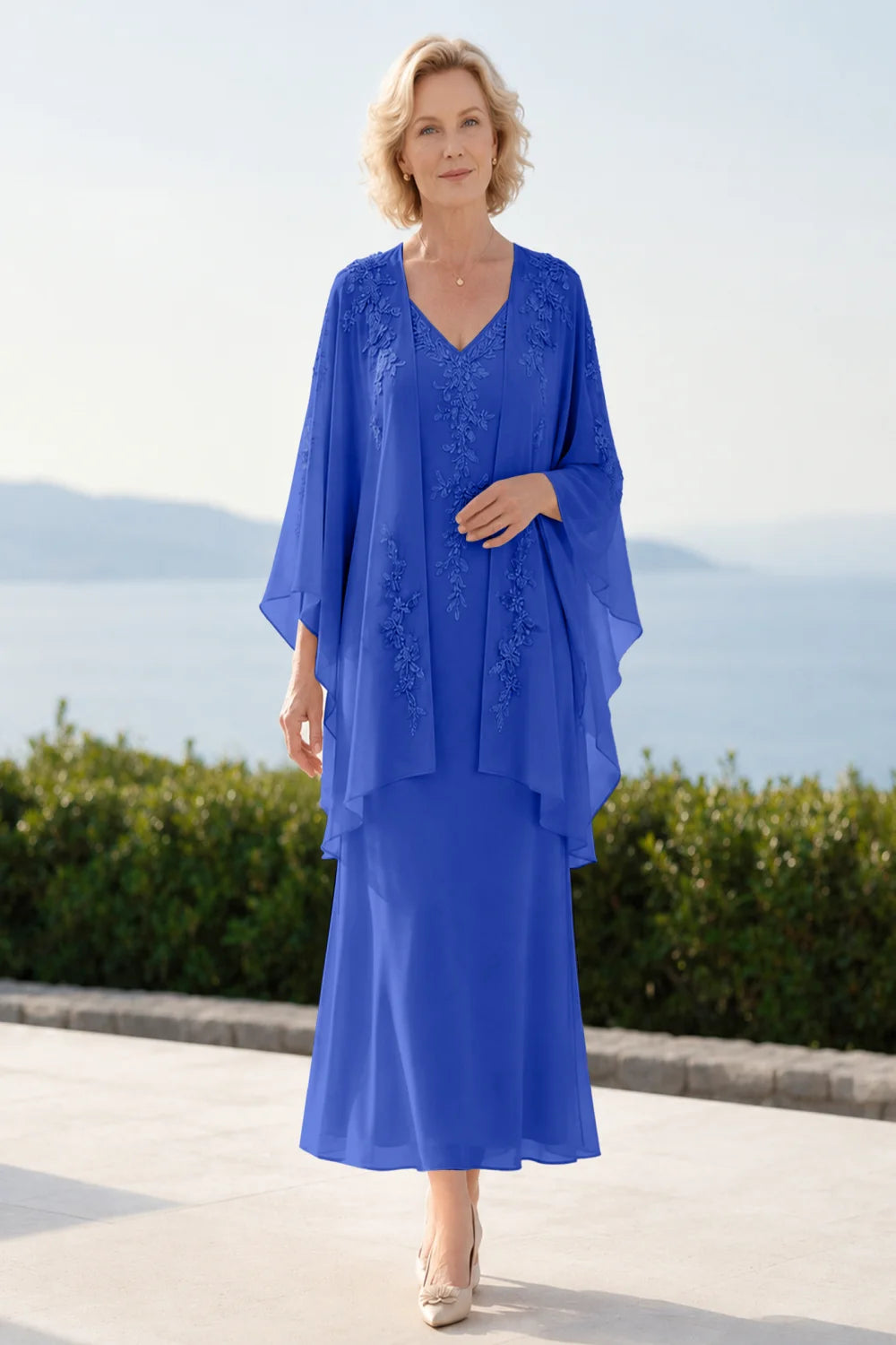 Front view of a royal blue dress with a decorated neckline and long upper overlay.