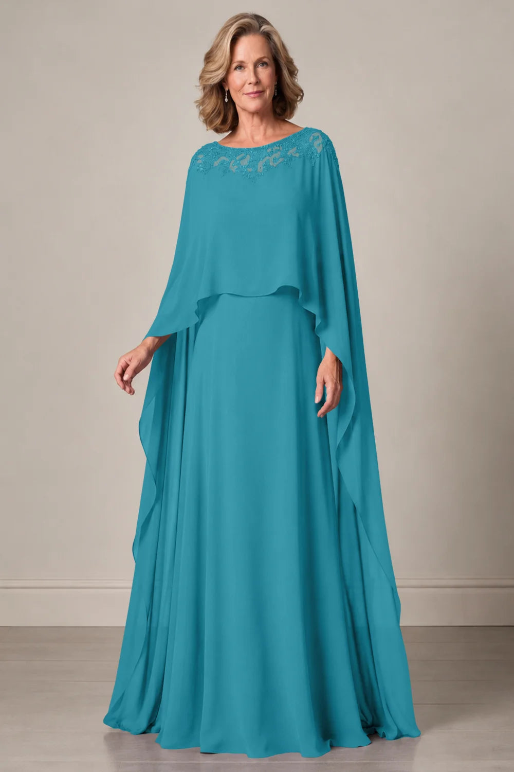 Front view of a teal dress with a decorated neckline and long cape panels.