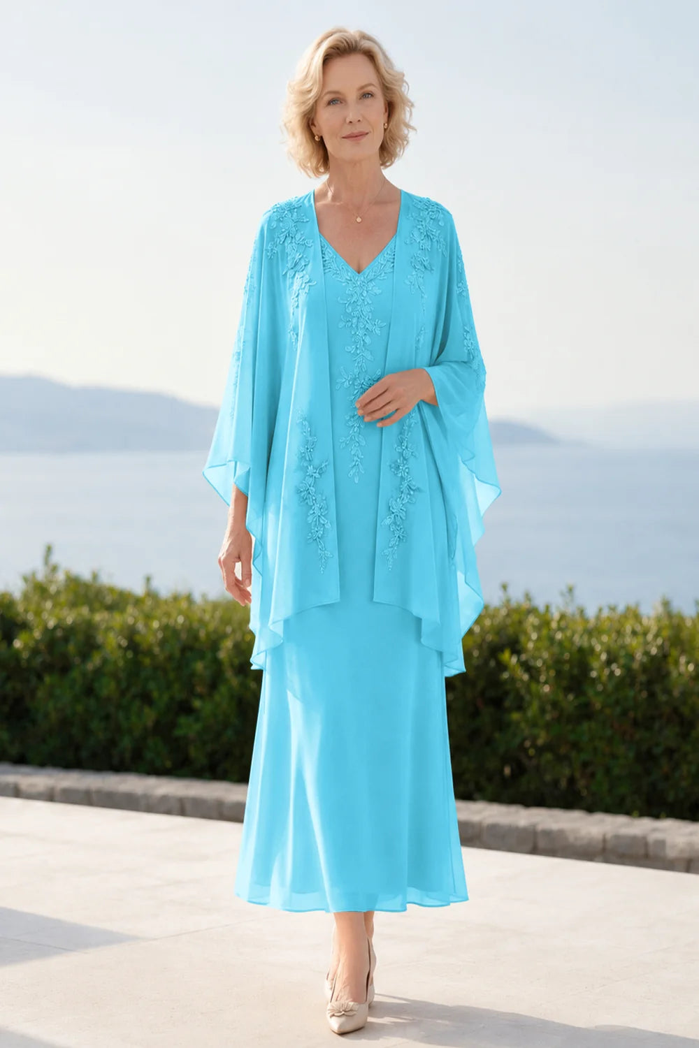 Front view of a turquoise dress with a decorated neckline and long upper overlay.